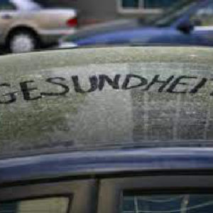 dark car covered with pollen, with "gesundheit" written in the pollen